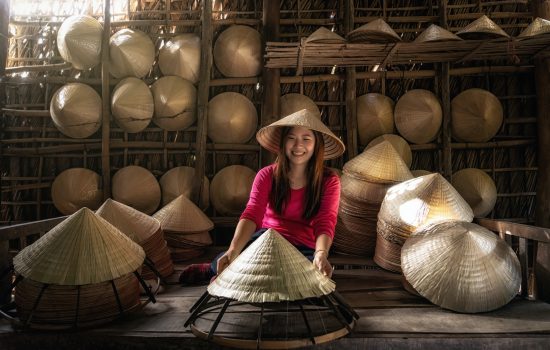 Asian traveler female craftsman making the traditional vietnam hat in the old traditional house